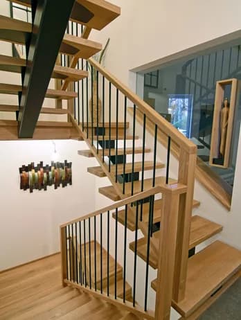 Moderne Holztreppe mit schwarzen Metallstäben und Holzgeländer