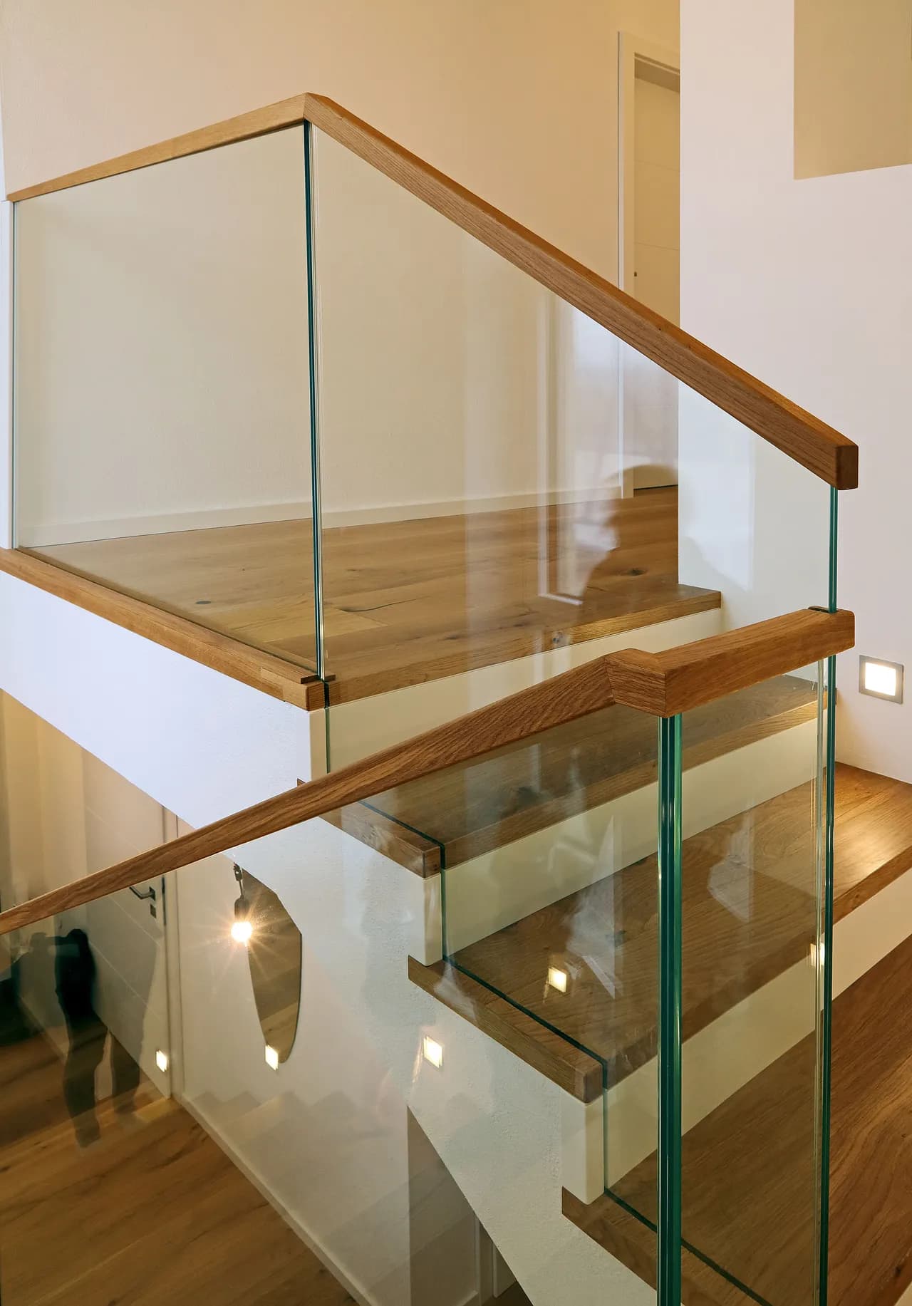 Elegante Glastreppe mit Holzgeländer und LED-Beleuchtung