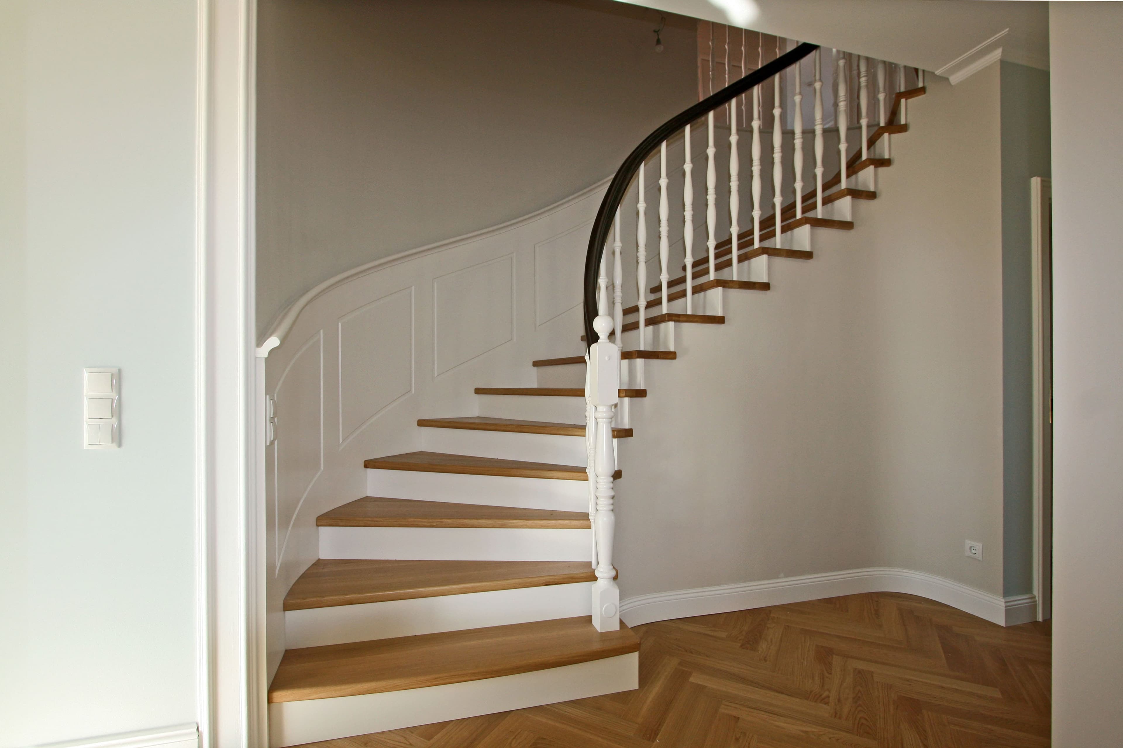 Geschwungene Betonstiege mit Massivholzstufen und klassischem Geländer - Bild 1