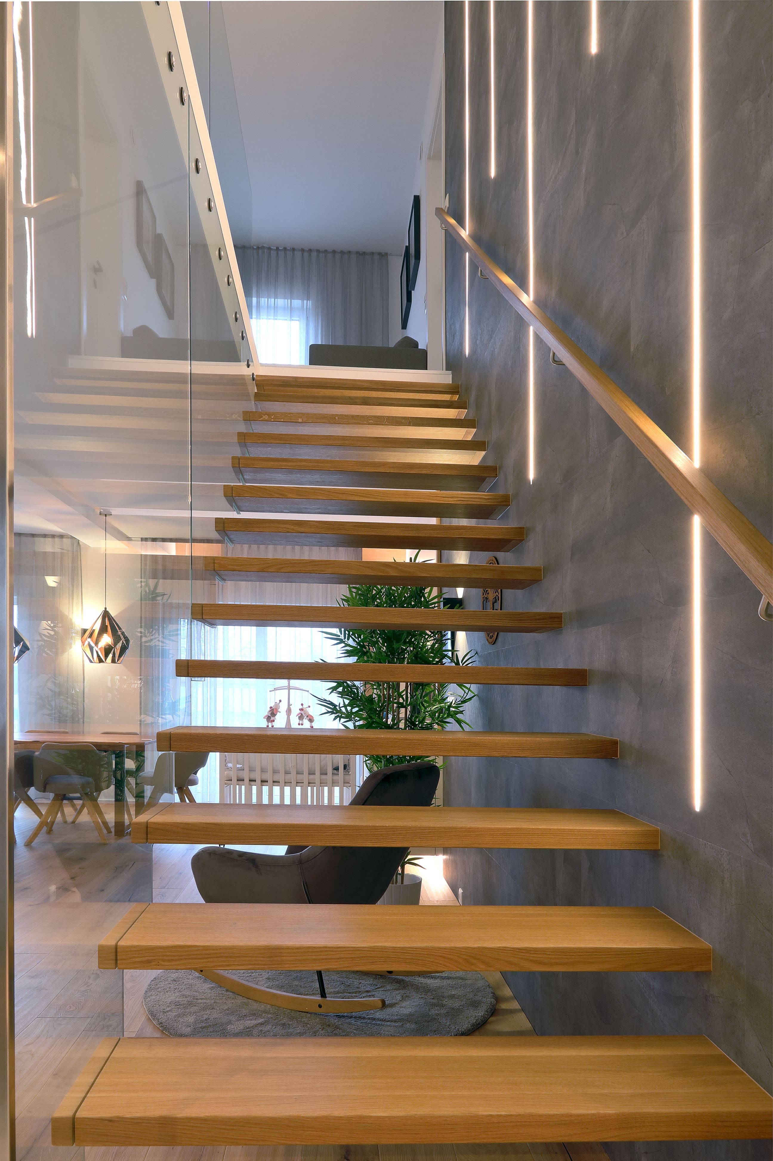 Moderne freitragende Holztreppe mit Glasgeländer und Lichtakzenten - Bild 3