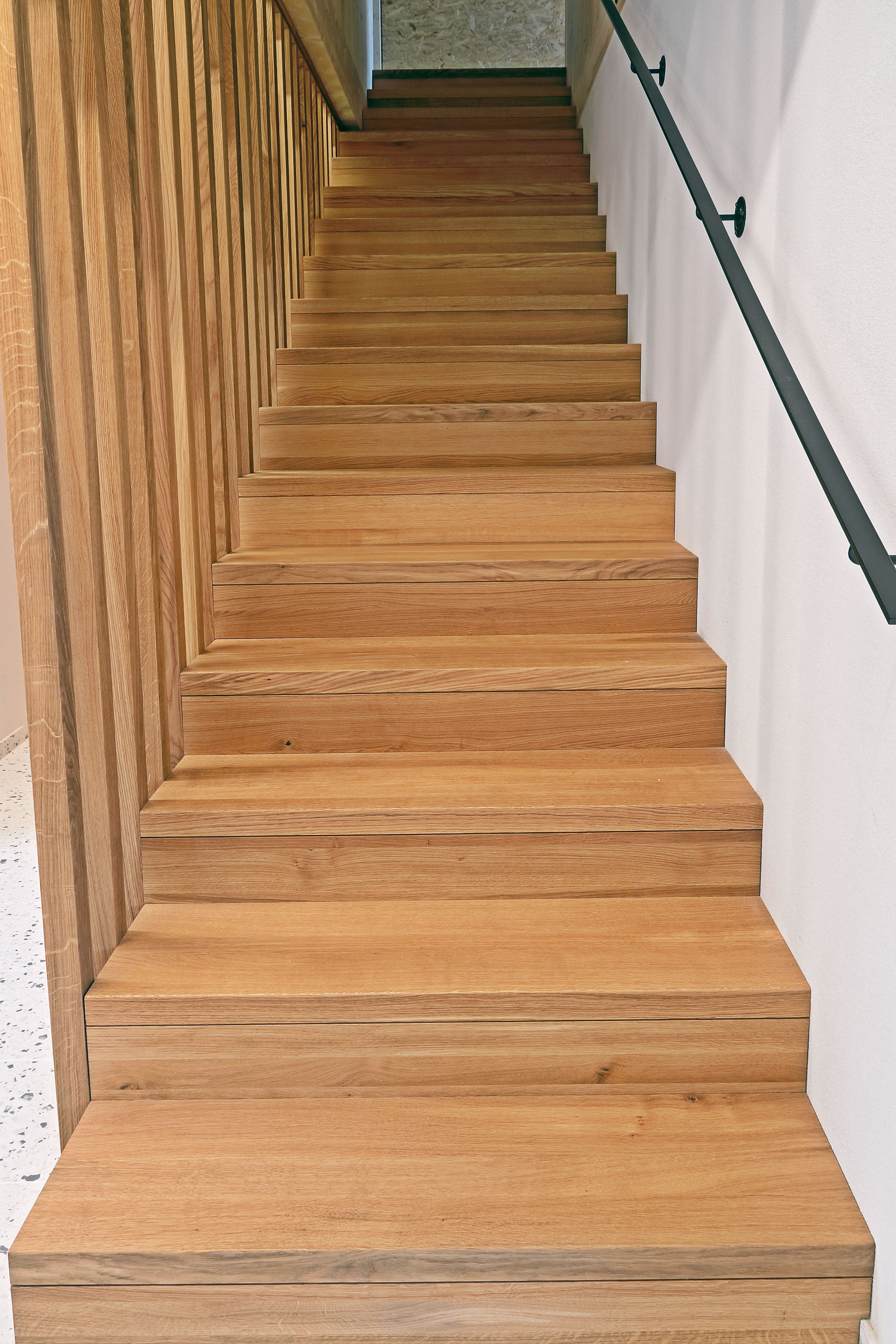 Holztreppe mit massiven Eichenstufen und Lamellenwand