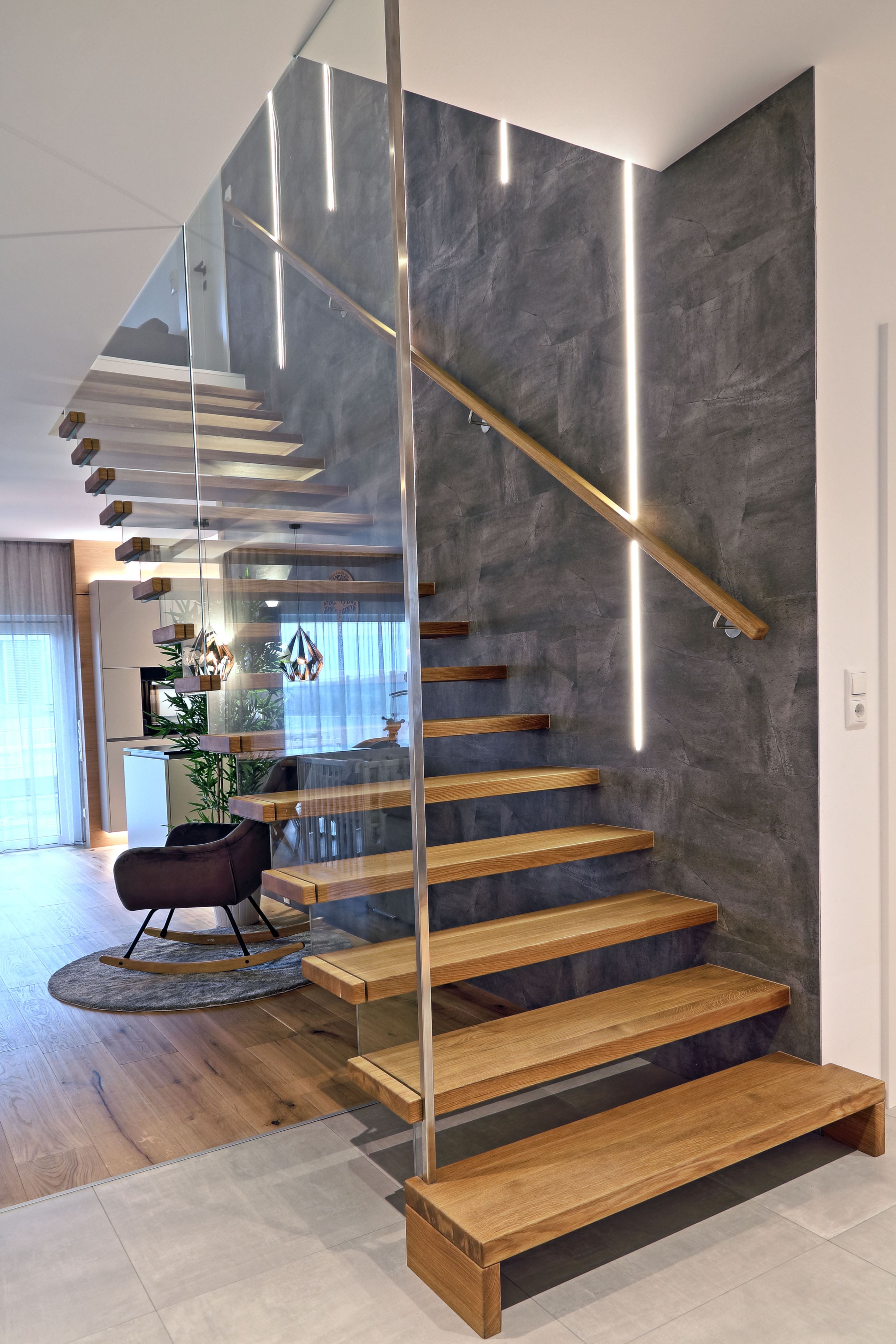 Moderne freitragende Holztreppe mit Glasgeländer und Lichtakzenten